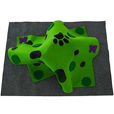 a green blanket with black spots and paw prints on the front, sitting on top of a gray surface