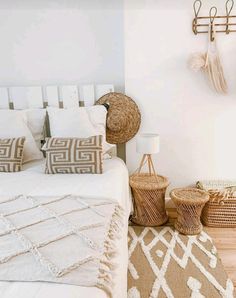 a bed with white sheets and pillows in a bedroom next to baskets on the wall