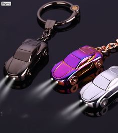 three car shaped key chains on a black surface with light coming from the front and back