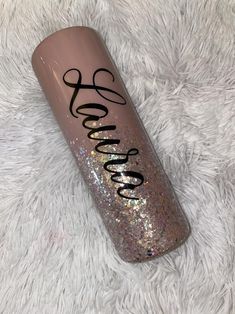 a pink and gold glitter tumbler with the word love on it sitting on a white carpet