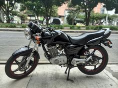 a motorcycle is parked on the side of the road in front of some trees and buildings