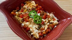 a red bowl filled with food on top of a wooden table