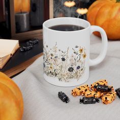 a cup of coffee and some cookies on a table with pumpkins in the background