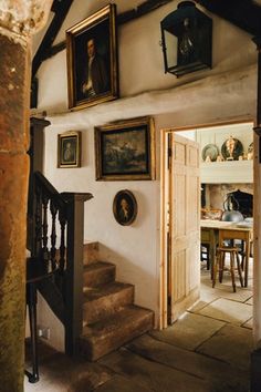 an entry way with paintings on the wall and stairs leading to another room in the house