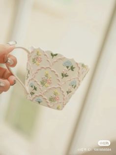 a hand holding a cup with flowers on it