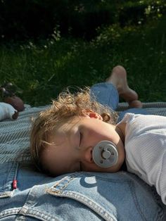 a little boy laying on top of a blanket with a pacifier in his mouth