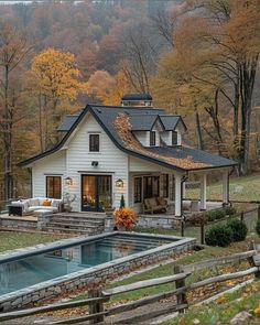 a white house with a pool in front of it and lots of trees surrounding it