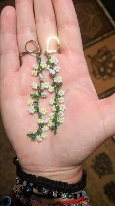 a person's hand holding some tiny white flowers and green leaves with a ring on it