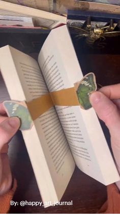 a person is holding a book with a butterfly on it and the pages have been cut out