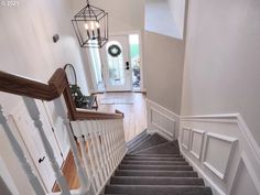 a staircase with gray carpet and white handrails leading up to the front door