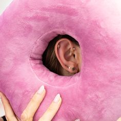 a woman holding a pink donut pillow in front of her face