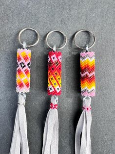 three keychains with different designs on them sitting next to each other in front of a gray surface