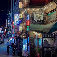 a city street at night with people walking on the sidewalk and neon signs hanging from buildings