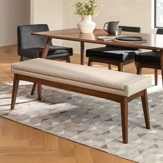 a dining room table with two chairs and a bench in front of it on top of a rug