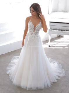 a woman in a white wedding dress standing next to a piano