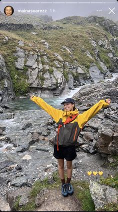 a man standing on top of a rocky hillside next to a river