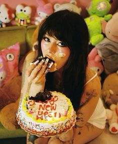 a woman eating a cake while sitting in front of stuffed animals