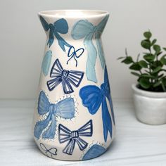 a blue and white vase sitting on top of a table next to a potted plant