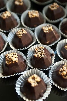 chocolates with nuts in the middle are arranged on a black table top, ready to be eaten