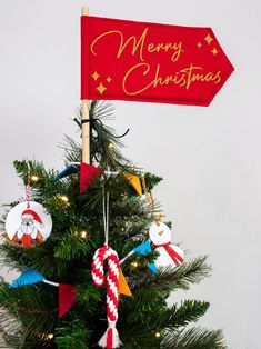 a christmas tree decorated with ornaments and a merry sign hanging from it's top