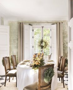 a dining room table is set for christmas with candles and greenery on the table