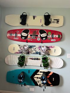 three snowboards mounted to the wall with shoes hanging on each one's sides