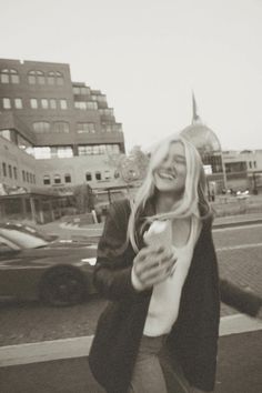 a woman is walking down the street and smiling