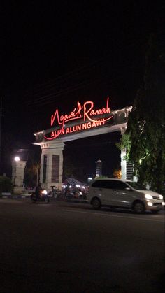 a white van driving past a tall building with a neon sign on it's side