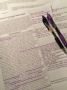 two pens sitting on top of an open page of paper with writing in purple ink