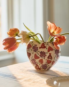 a vase filled with flowers sitting on top of a wooden table next to a window