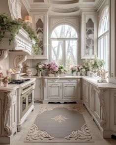 a kitchen with white cabinets and flowers in vases on the windows sill above the stove