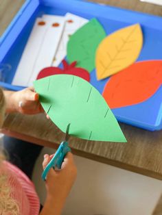 a child cutting out leaves with scissors on a table