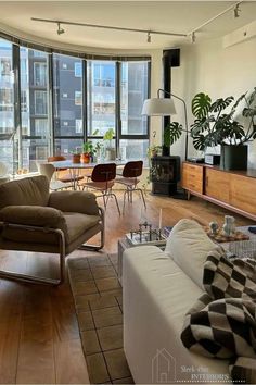 a living room filled with lots of furniture and tall windows next to a wooden floor