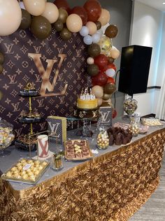 a table topped with desserts and balloons in front of a large louis vuitton sign