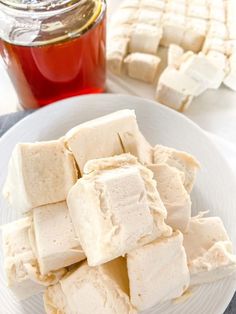 several pieces of tofu sitting on a plate next to a jar of honey