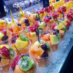 many different kinds of fruit in plastic cups