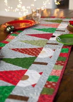 the table is set for christmas dinner with green plates and silverware on top of it