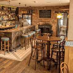 a bar with several stools and wooden tables