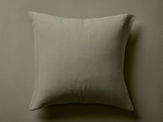 a white pillow sitting on top of a bed next to a wall with a light green background