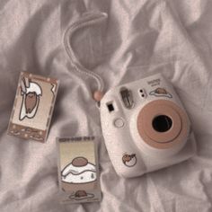 a polaroid camera sitting on top of a bed next to two small stickers