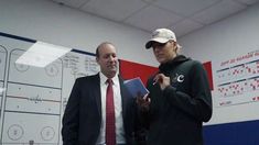 a man in a suit and tie standing next to a woman holding a clipboard