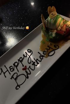 a birthday cake with the words happy birthday written in black writing on it, sitting on a white plate