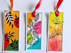 three bookmarks with different designs on them hanging from red string and two are decorated with orange ribbons