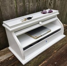 a white wooden entertainment center with sunglasses and cell phone on it's top shelf