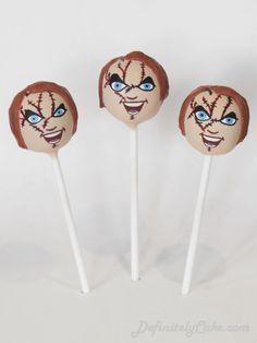 three halloween lollipops with faces painted on them are sitting side by side