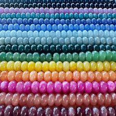 many different colors of beads are arranged in the shape of a rainbow - hued background