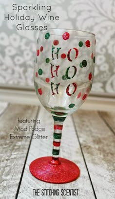 a wine glass with the words sparkling holiday wine glasses painted on it, sitting on a wooden table