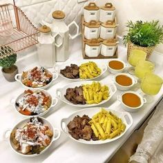 a table topped with plates of food next to cups of sauces and condiments