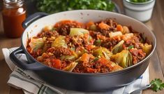 a pot filled with cabbage and meat on top of a wooden table next to vegetables