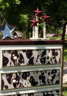 a cow print dresser with three stars on top and two other items sitting on top